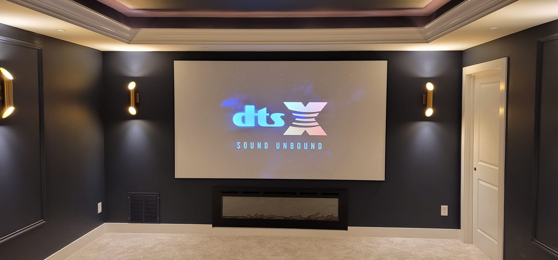 Dedicated luxury home theater installation by Noble A-V featuring tiered seating and stained-wood acoustic finish