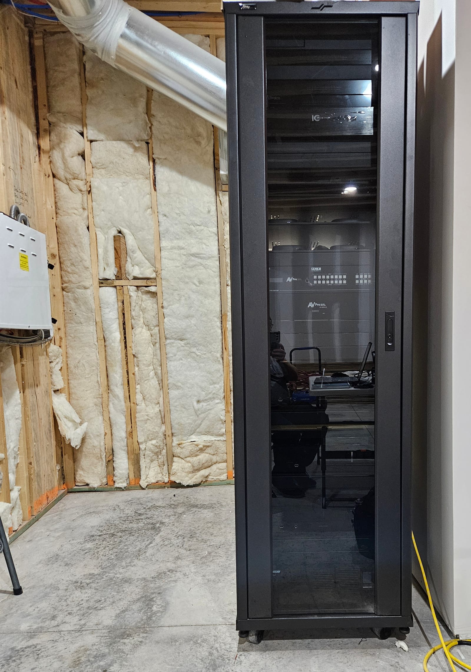 Full-height glass-front equipment cabinet with integrated AV processors and matrix switching